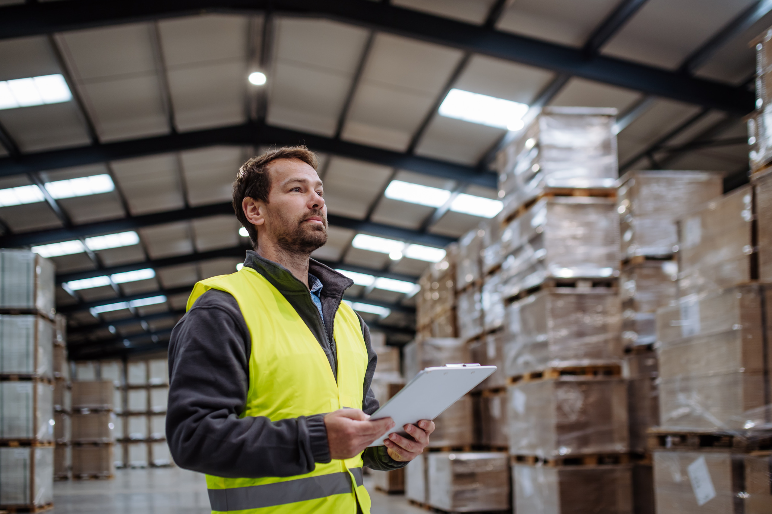 portrait of warehouseman with clipboard checking delivery, stock in warehouse. warehouse worker preparing products for shipment.